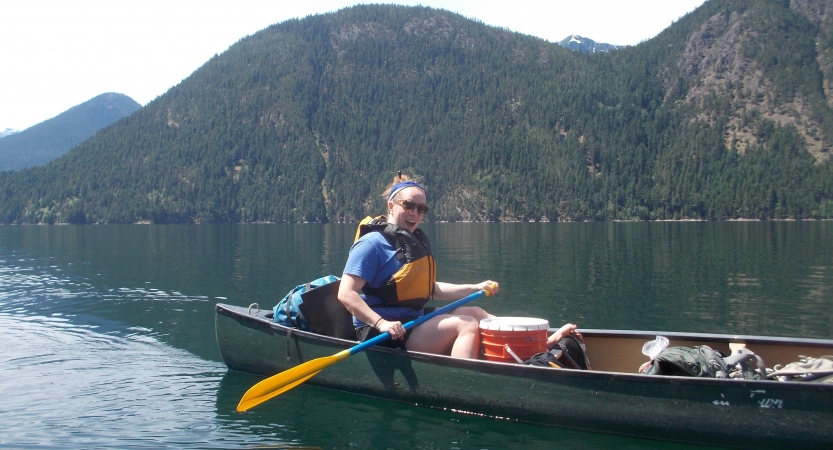 a student paddles a canoe on still water on an outward bound course in the pacific northwest